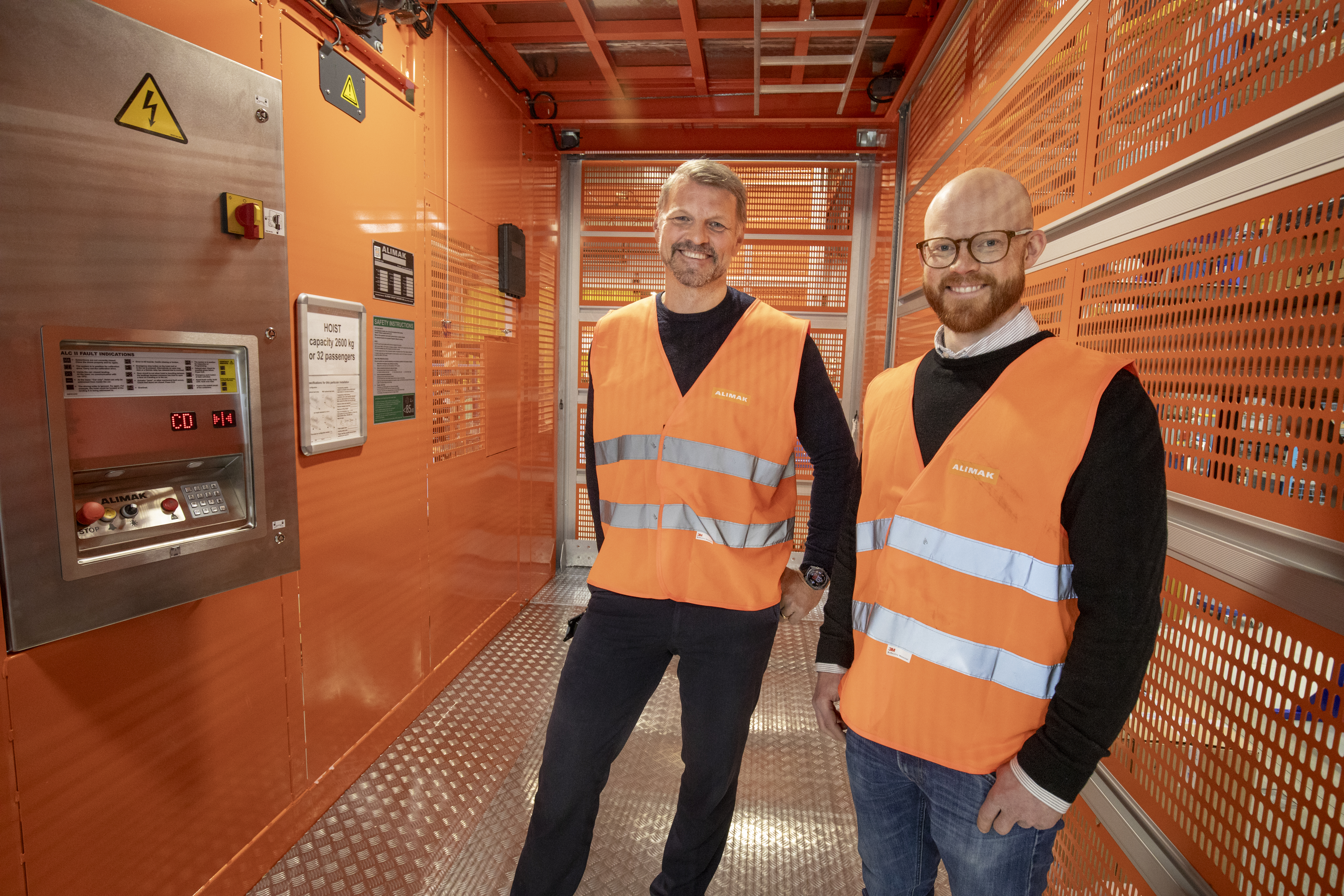 Alimaks globala fabrikschef Patrik Sundqvist och skellefteåfabrikens VD Ola Adamsson i en färdigmonterad bygghiss för persontransport.